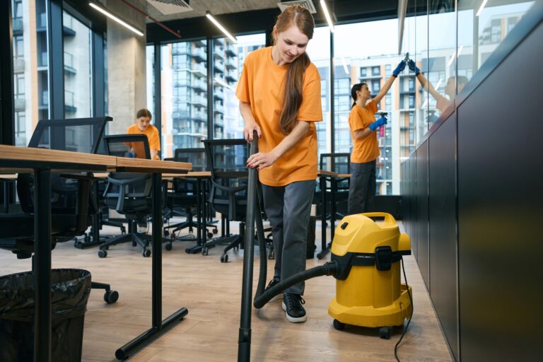 Female cleaning company team in overalls cleans and disinfects coworking space