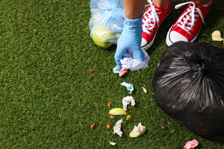 Garbage bags with rubbish, feets and hand on green background, space for text